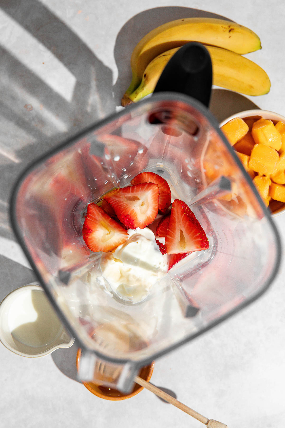 Strawberries, milk, yogurt and honey in a blender jar.