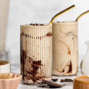 Two glasses of chocolate peanut butter smoothie sitting on a white countertop.