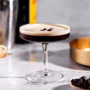 A tequila espresso martini sitting on a marble counter.