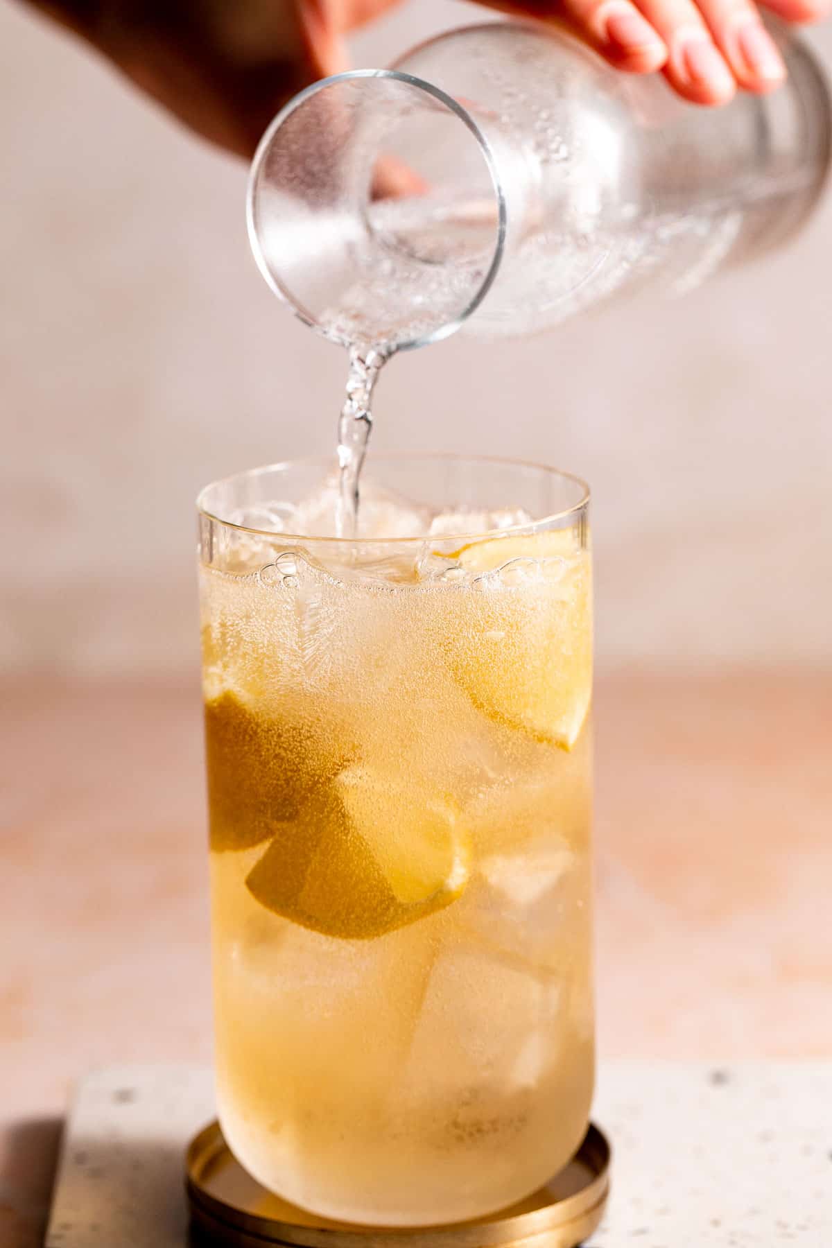 7UP pouring into a highball glass filled with ice and whiskey.