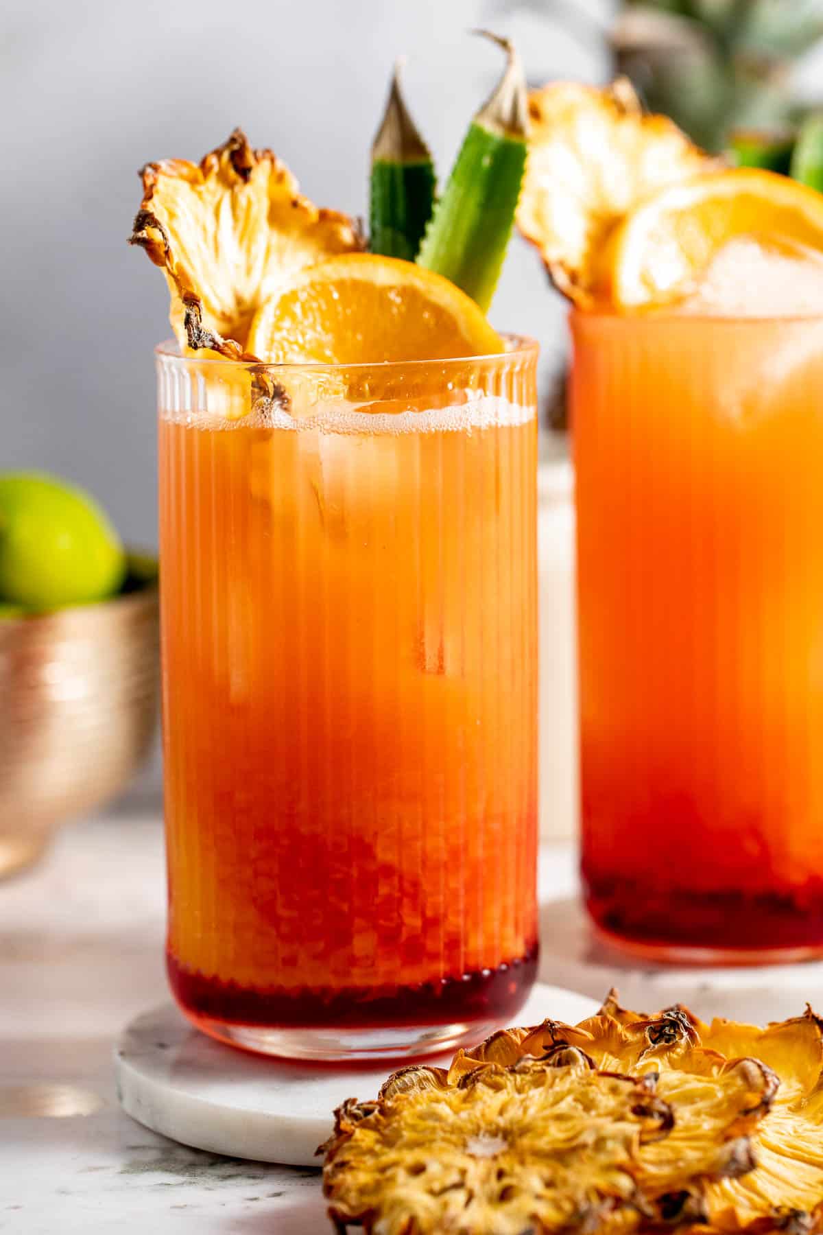 Two tall glasses filled with bay breeze cocktail sitting on a counter.
