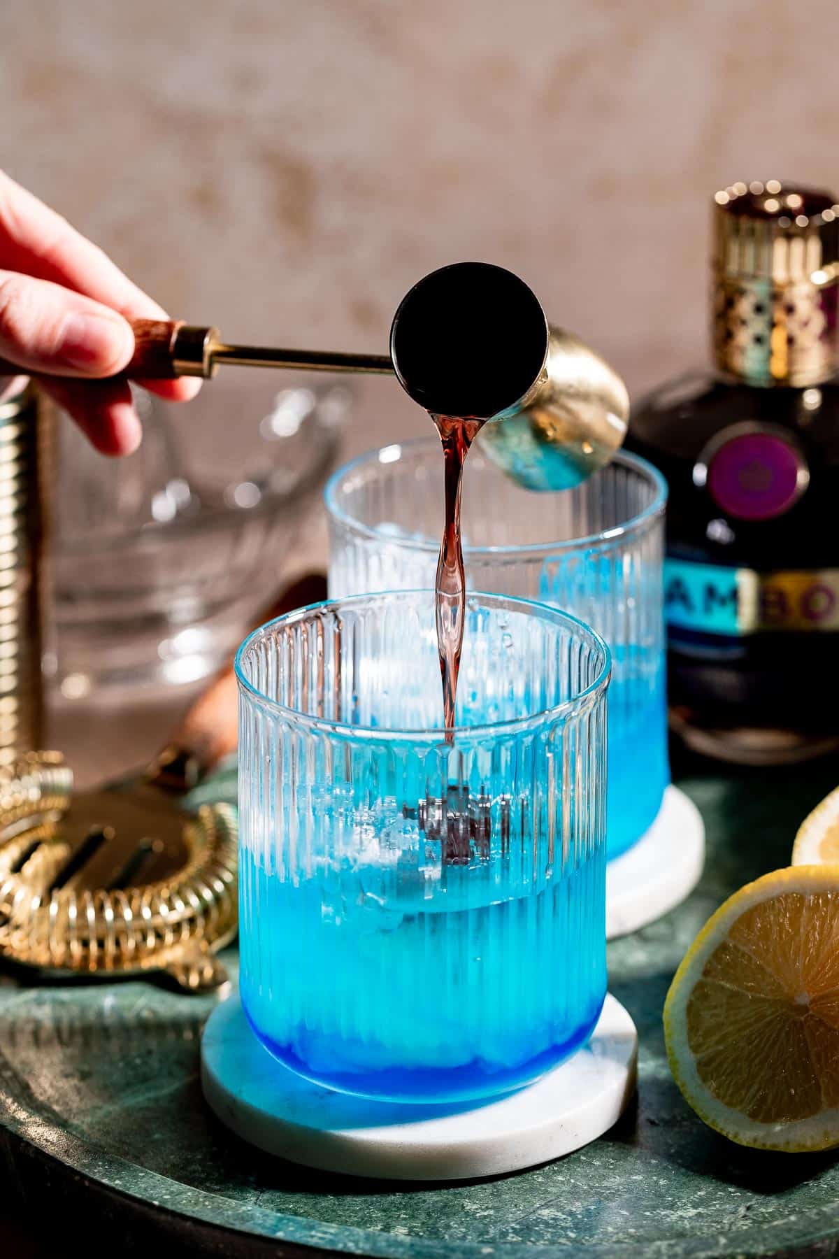 Adding blackberry liqueur to a partially mixed black opal cocktail.