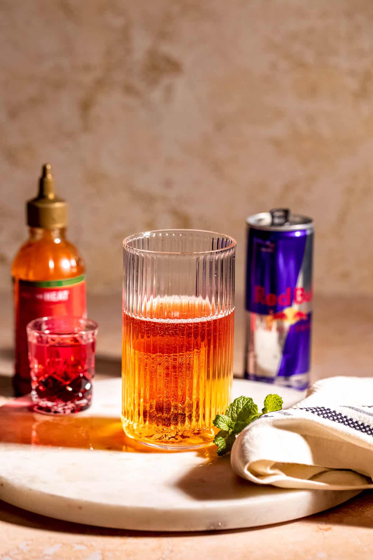 A Chuck Norris shooter sitting on a marble tray next to a can of Red Bull.