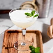 A southside cocktail served in a coupe glass and garnished with fresh mint leaves.