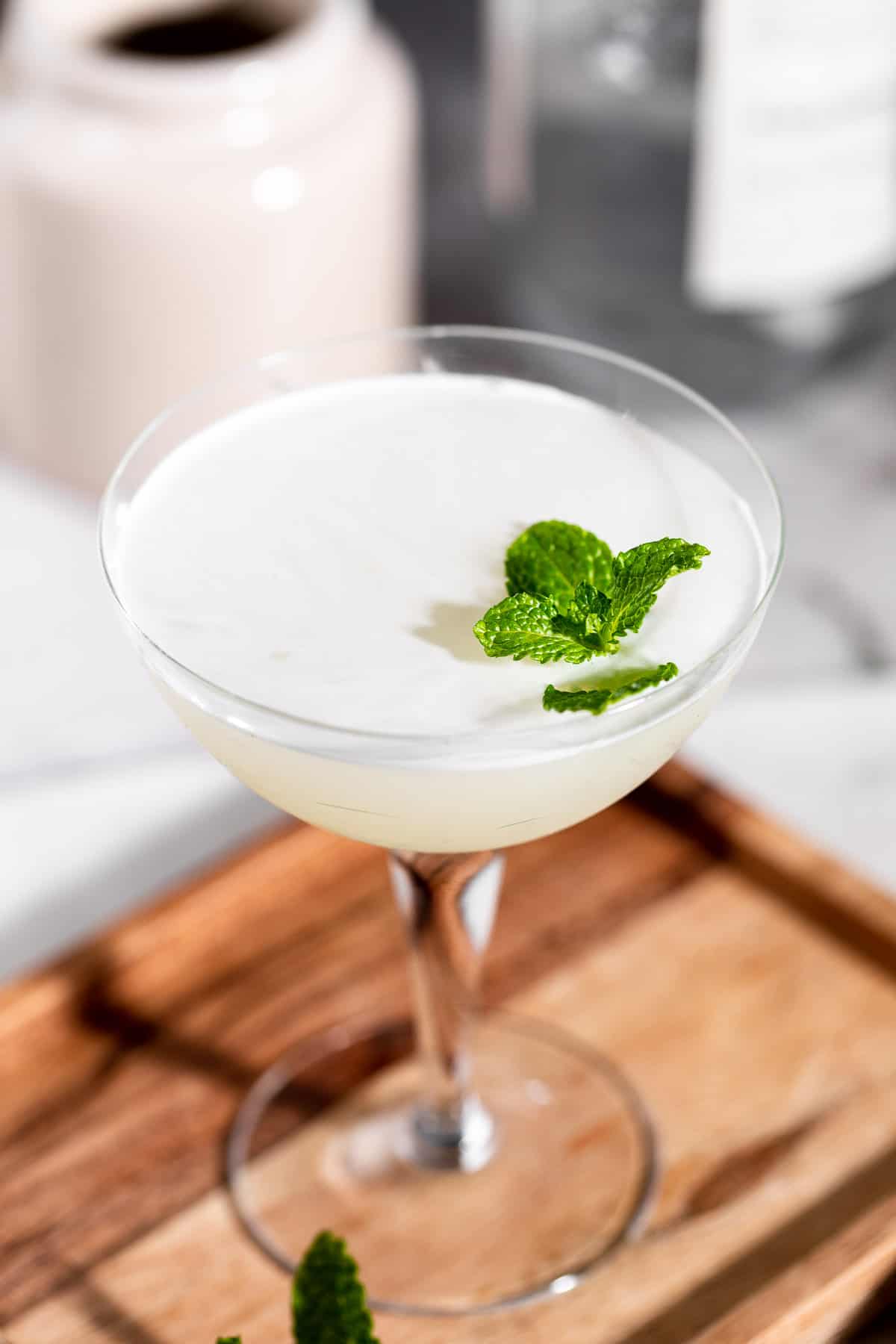 A Southside Cocktail served in a coupe glass and garnished with fresh mint.