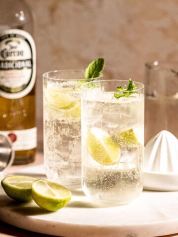 Two highball glasses of tequila and sprite sitting on a marble tray.