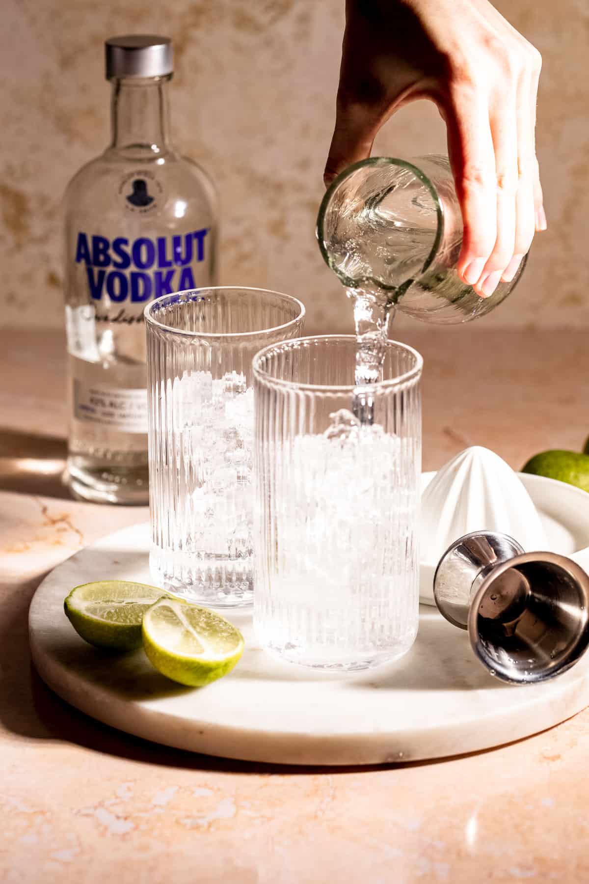 Sprite being poured into a highball glass that is filled with ice.