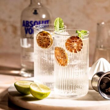 Two highball glasses filled with vodka and Sprite sitting on a marble tray.