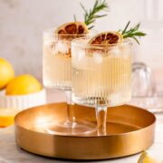 Two glasses of whiskey and tonic sitting on a gold serving tray.