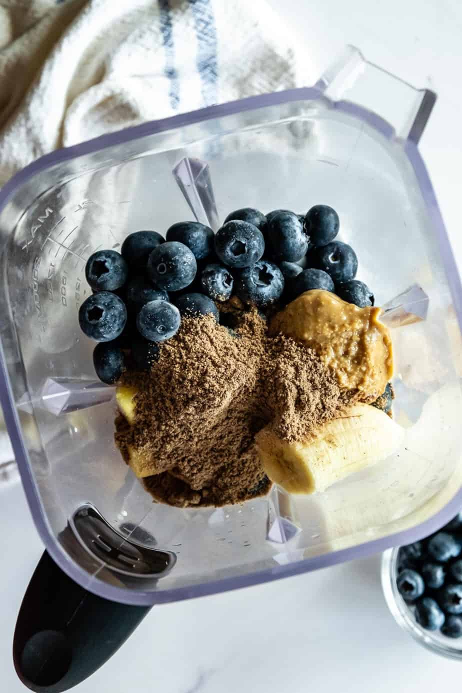 Ingredients for a blueberry pineapple smoothie inside a blender.