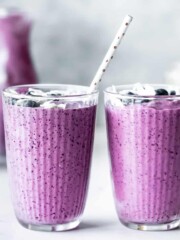 Two blueberry pineapple smoothies sitting on a countertop.