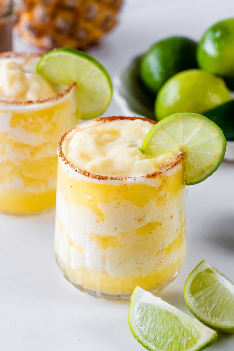 A frozen spicy pineapple margarita garnished with a lime wheel.