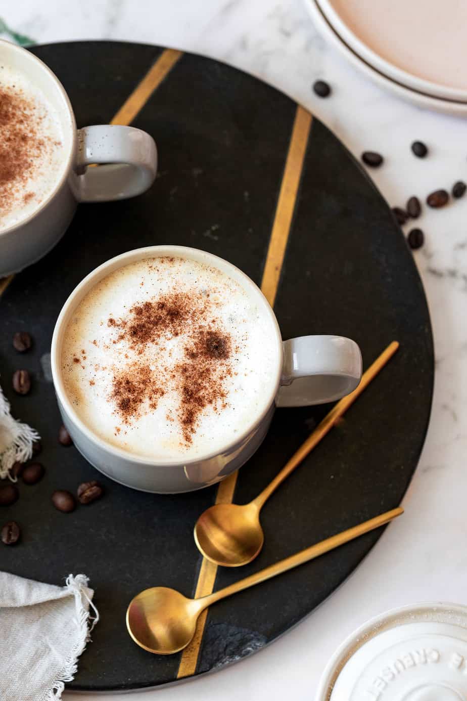 An oat milk latte served in a coffee mug and topped with a sprinkle of cinnamon.