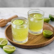 Two glasses of Tokyo Tea sitting on a round wooden tray.