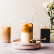 A tall glass of honey almond milk cold brew sitting on a small plate.