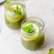 Two glasses of iced matcha lemonade sitting on a countertop.