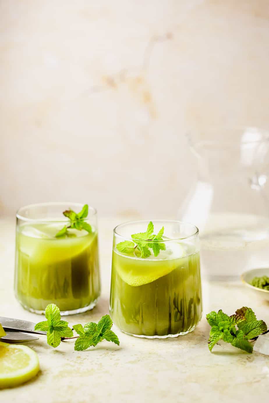 Two glasses of iced matcha lemonade garnished with fresh mint.