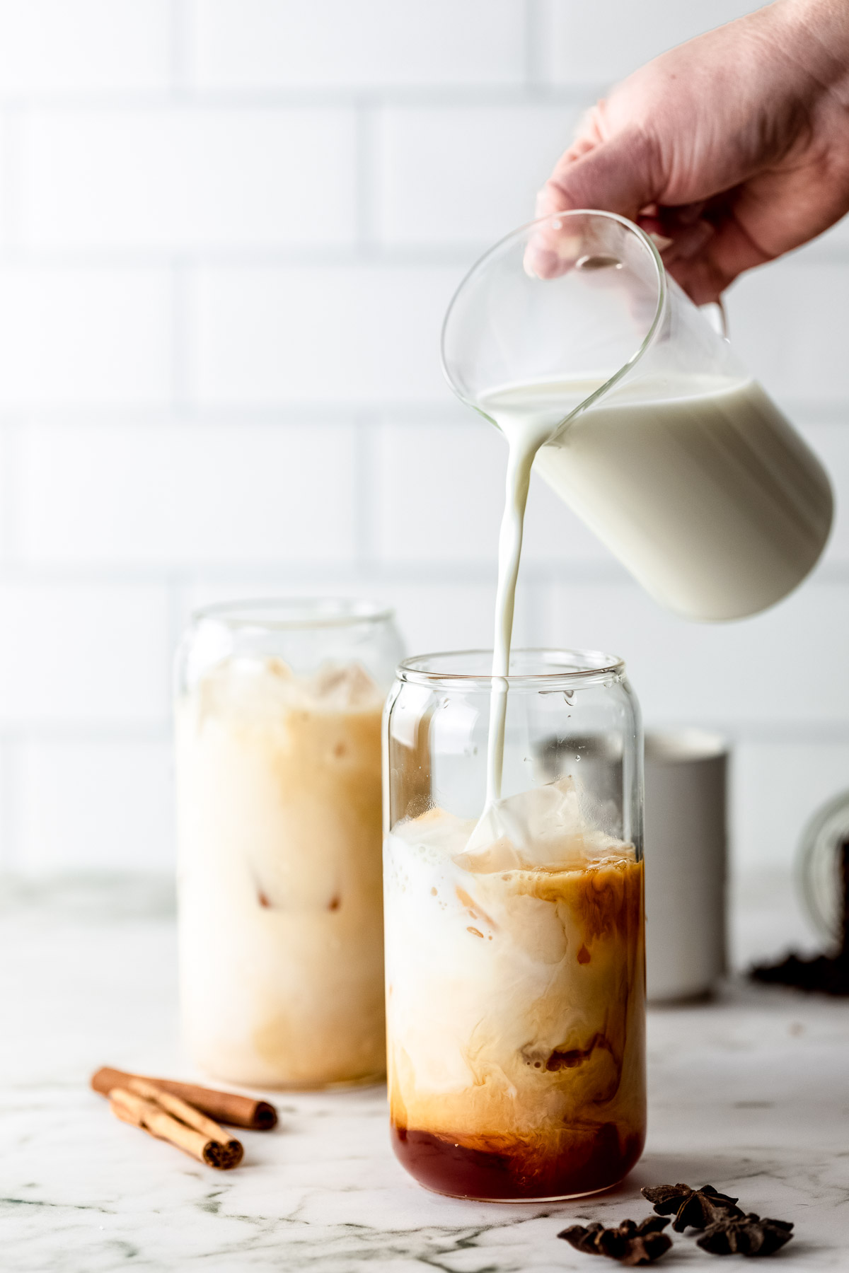 Milk pouring into a serving glass from a jug.