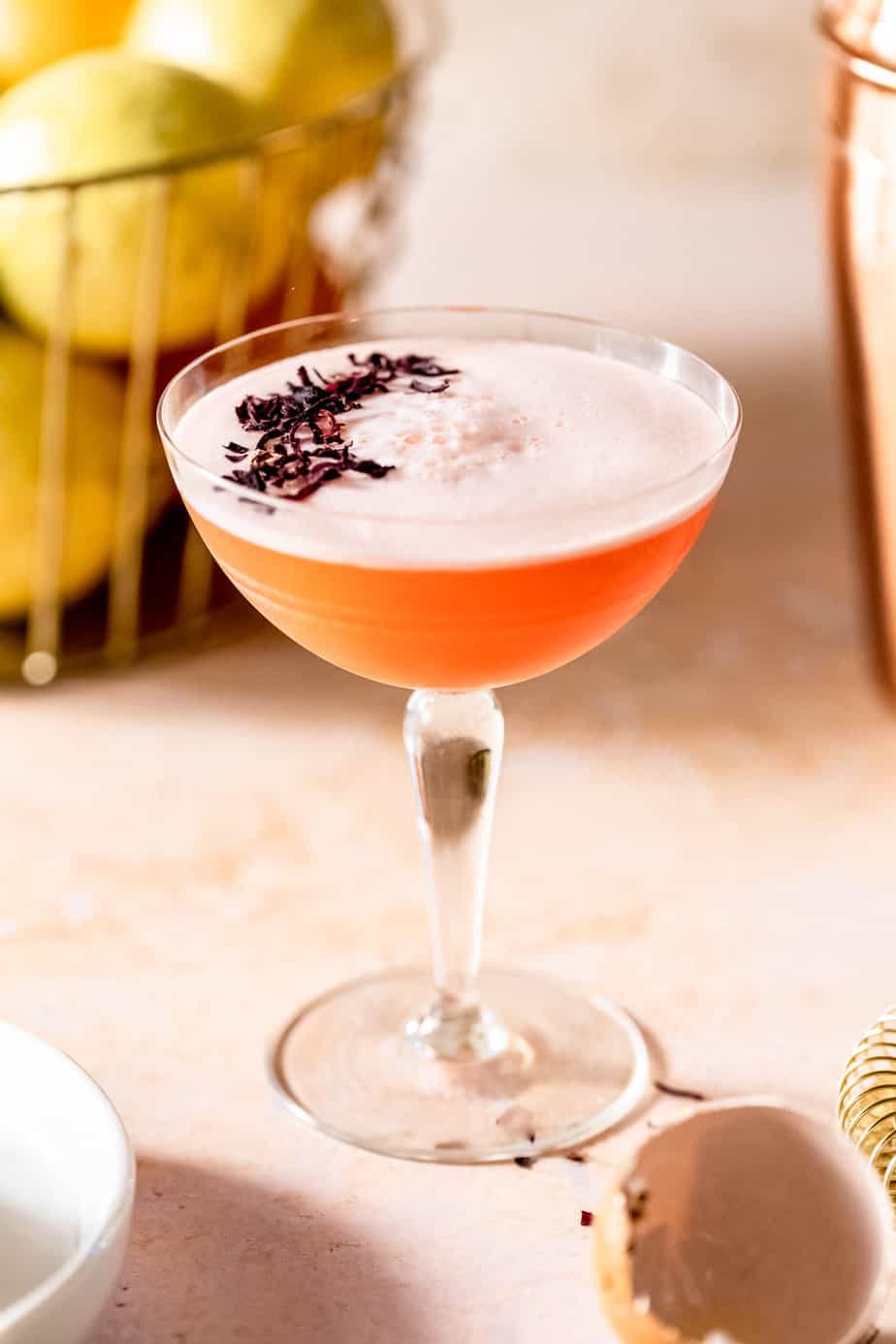 An Aperol gin cocktail garnished with dried flowers sitting on a table.