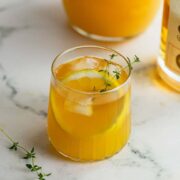 A glass of whiskey and orange juice sitting on a marble counter.