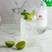 A glass with gin and Sprite sitting next to a bottle of gin.