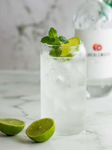 A glass with gin and Sprite sitting next to a bottle of gin.