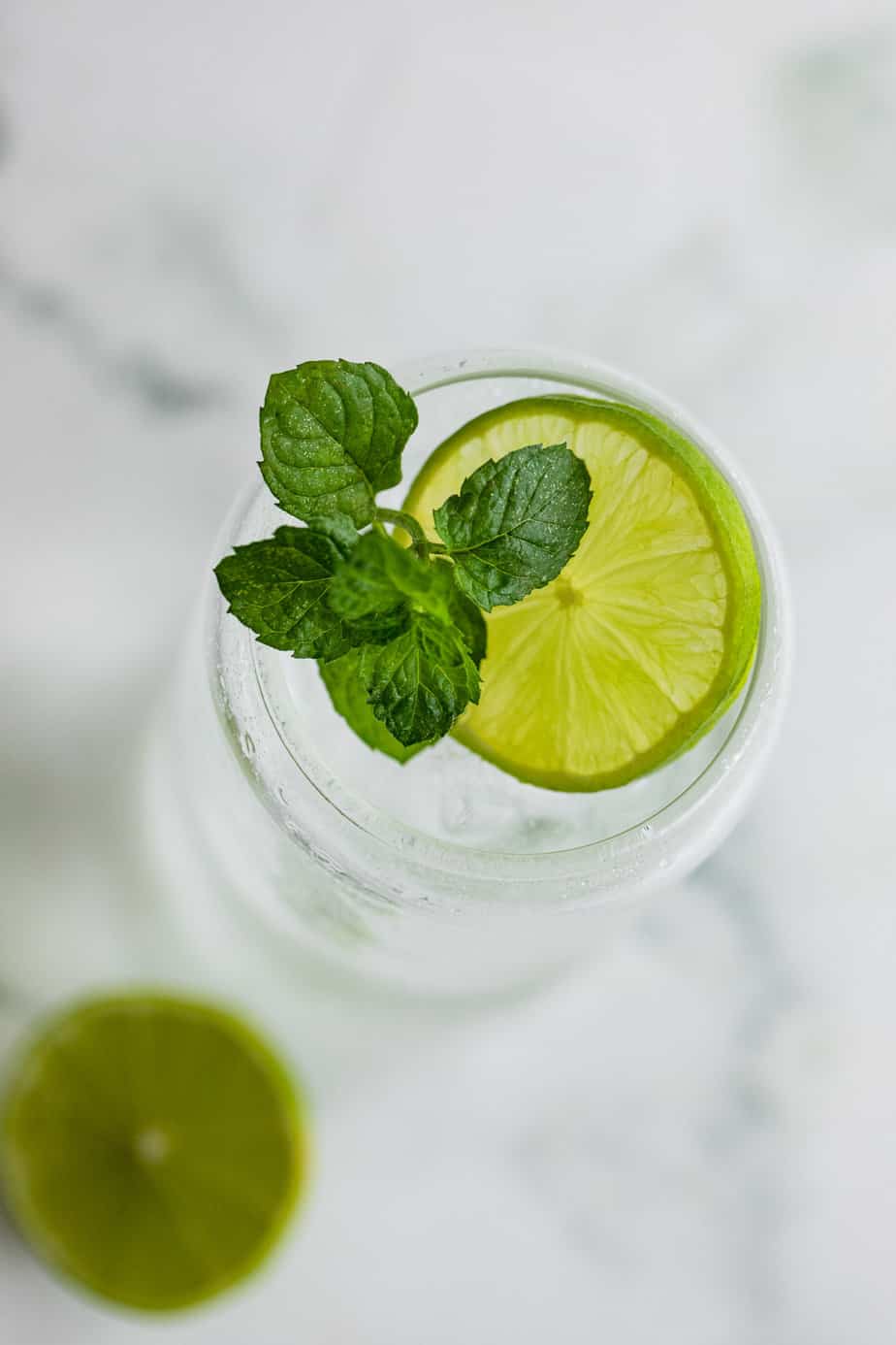 A gin and Sprite garnished with a lime wheel and fresh mint leaves.