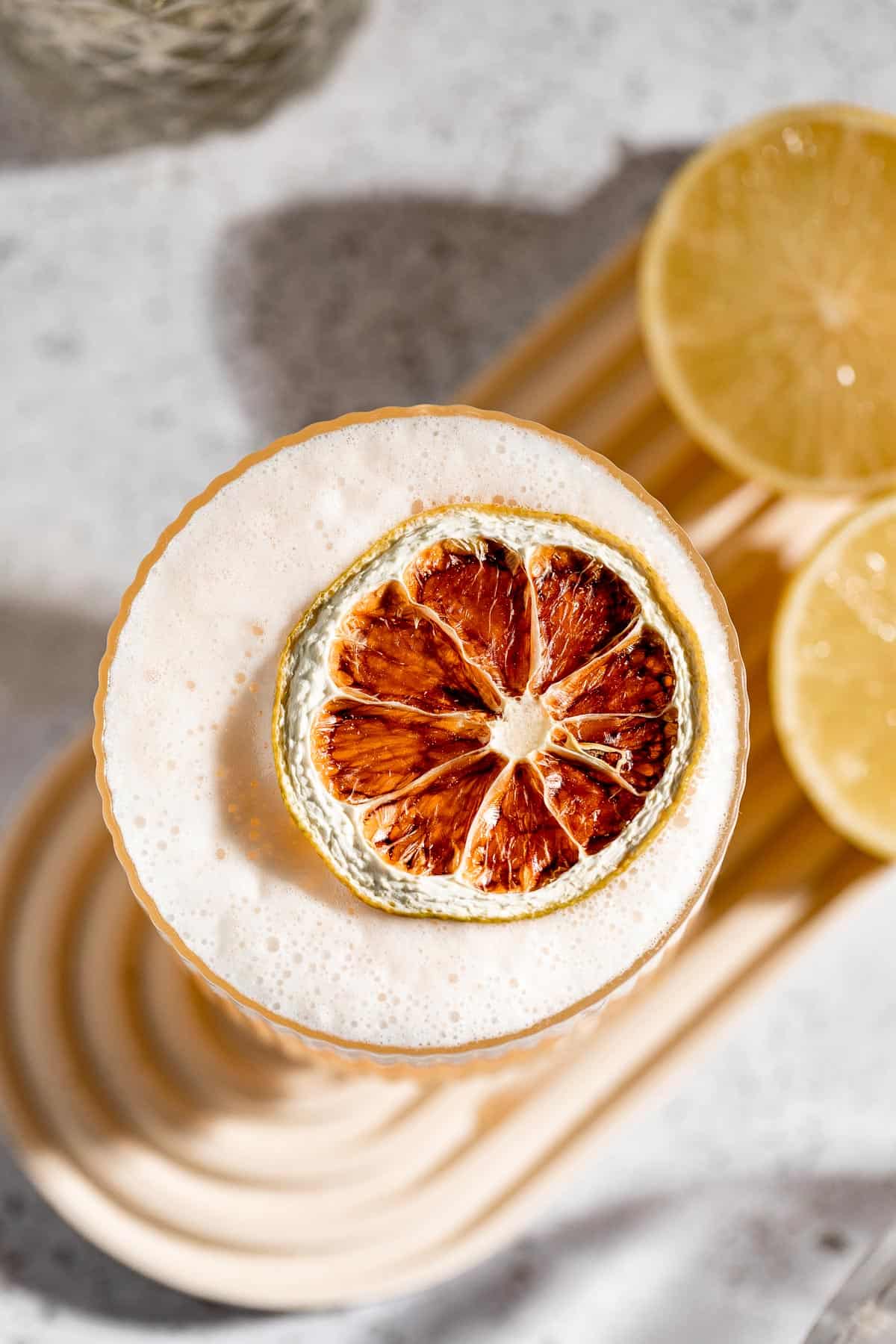 A vodka sour served in a rocks glass and garnished with a dried lemon slice.