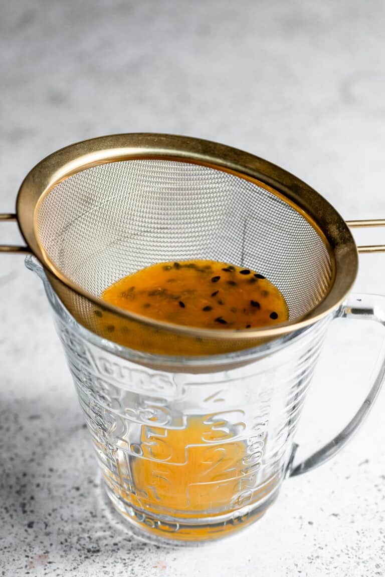 Passion fruit pulp being strained through a sieve.