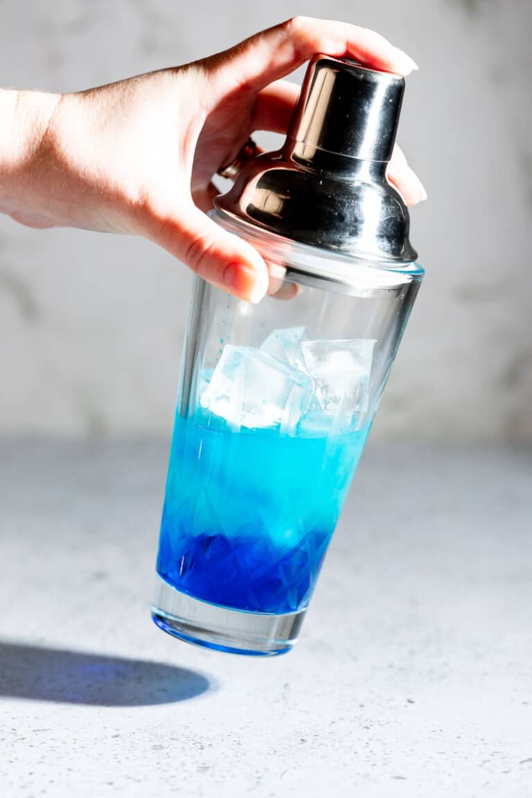 A blue motorcycle drink being shaken in a glass cocktail shaker. 
