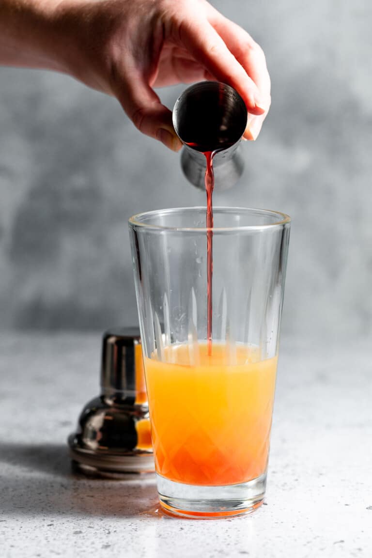 Passoa liqueur being poured into a cocktail shaker.