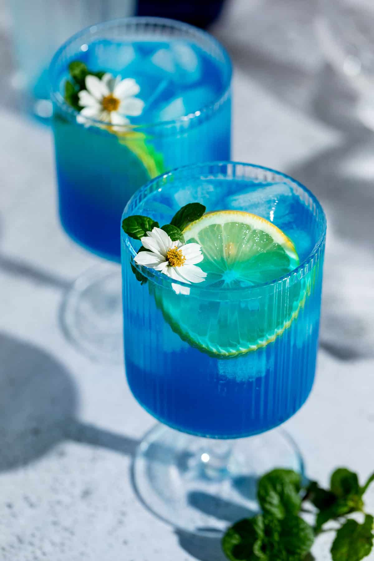 Two blue motorcycle drinks served in tall glasses garnished with lemon slices.