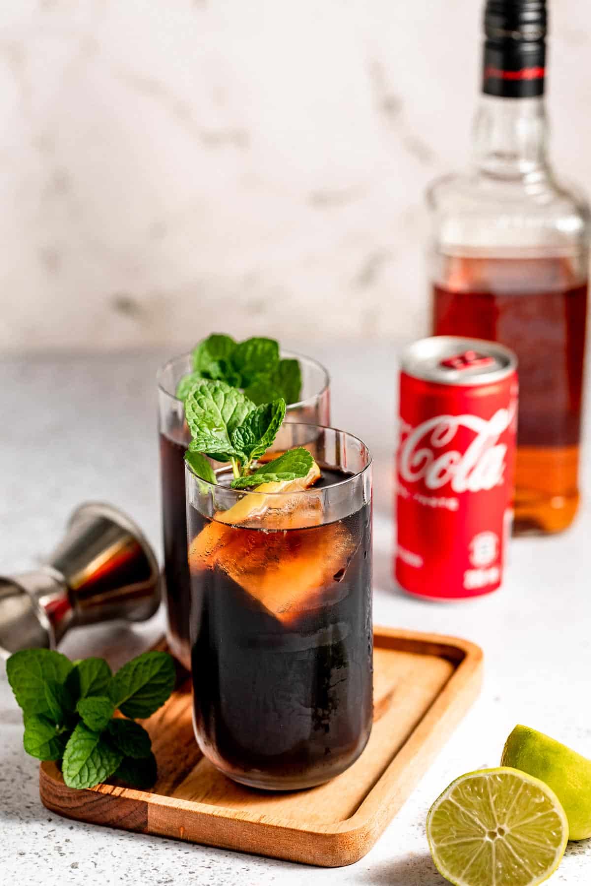 jack and coke on wooden tray with mint and lemon