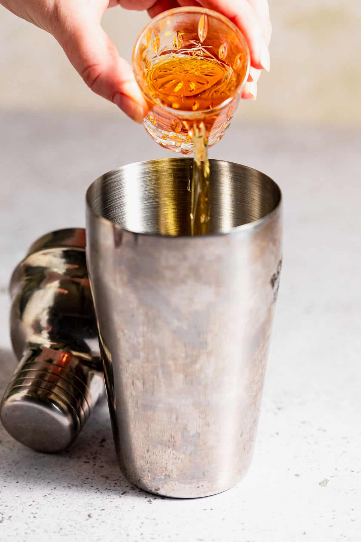 Amaretto being poured into a cocktail shaker.