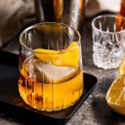 A Godfather drink served in a lowball glass with a lemon twist.