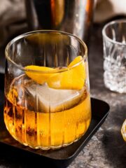 A Godfather drink served in a lowball glass with a lemon twist.