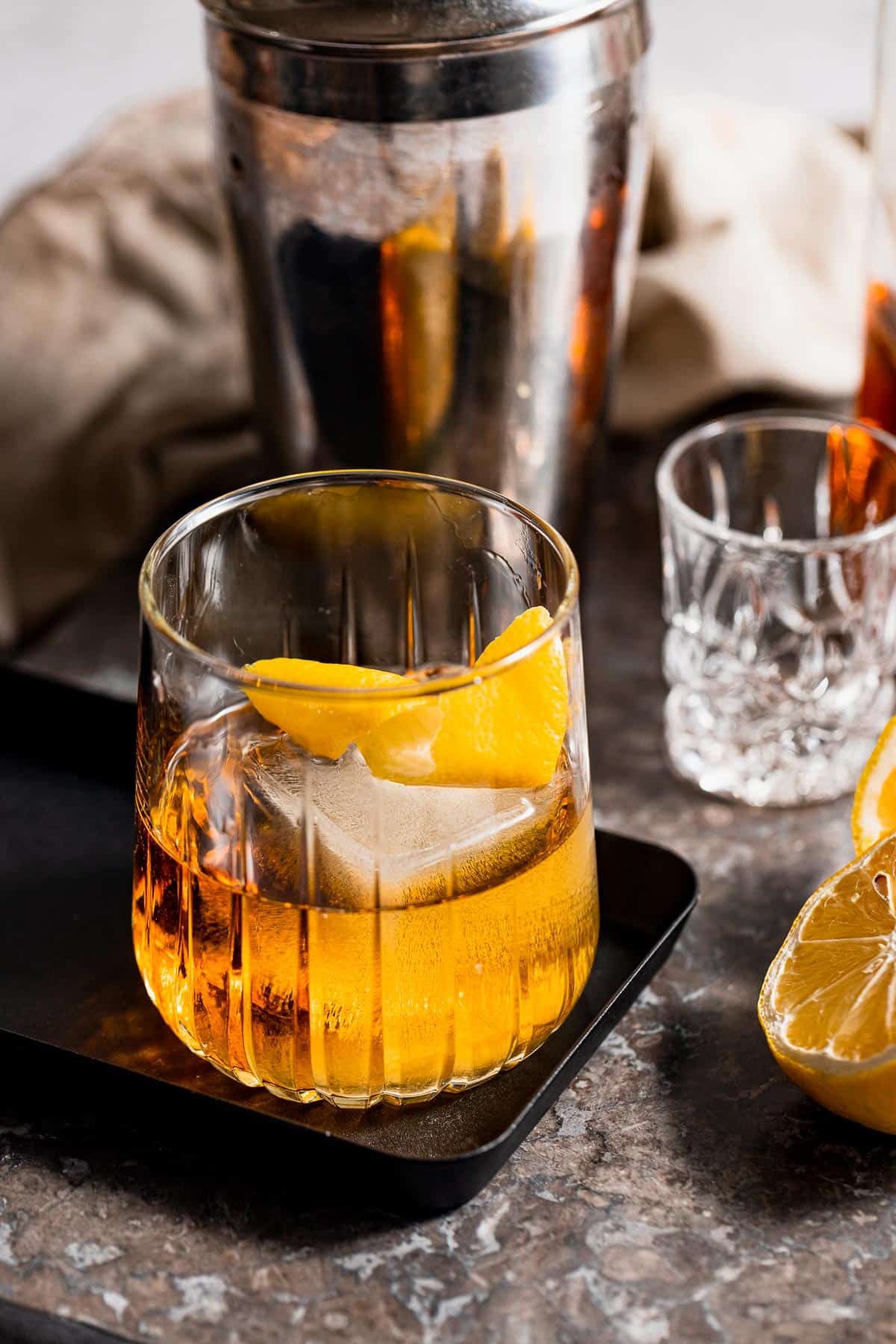 A Godfather Cocktail served with ice and lemon zest on a small tray.