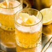 A gold rush cocktail served in an old fashioned glass on a gold tray.