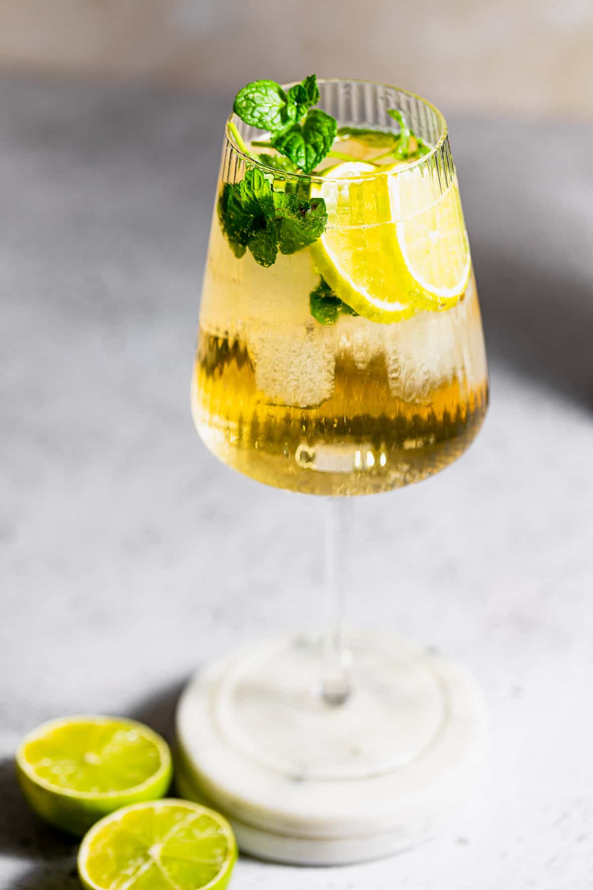 A hugo spritz cocktail in tall wine glass with fresh mint and lemon.