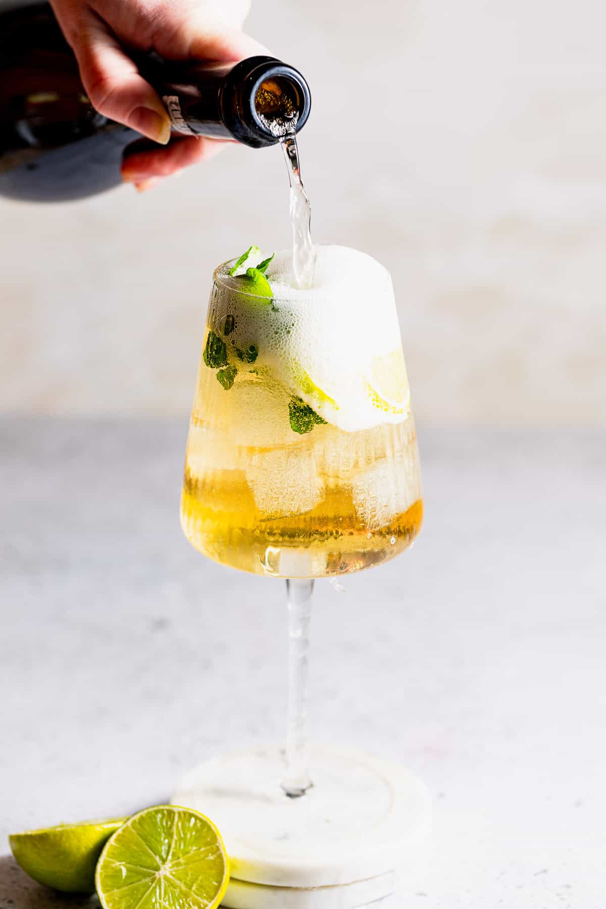 Prosecco being poured into a wine glass to complete the Hugo Spritz cocktail.