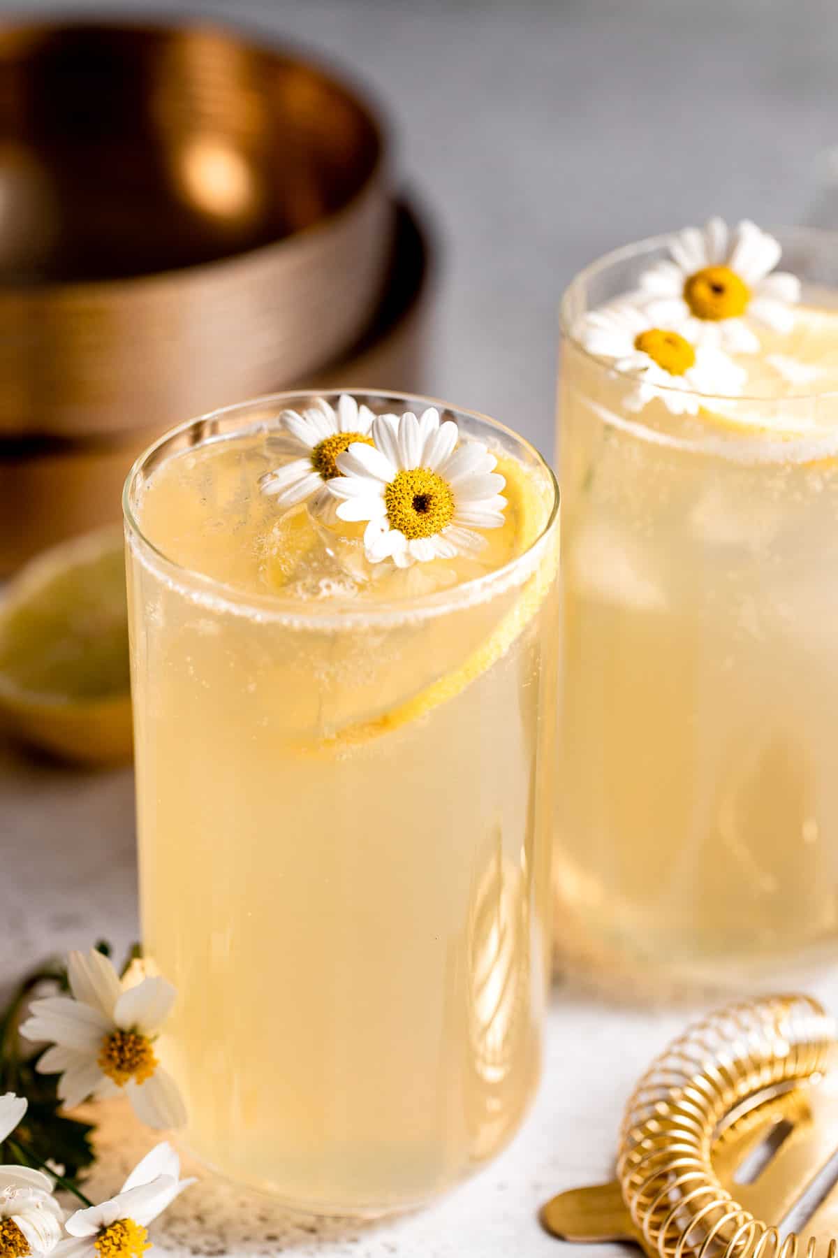 Two Lynchburg lemonades served in tall glasses and garnished with fresh flowers.