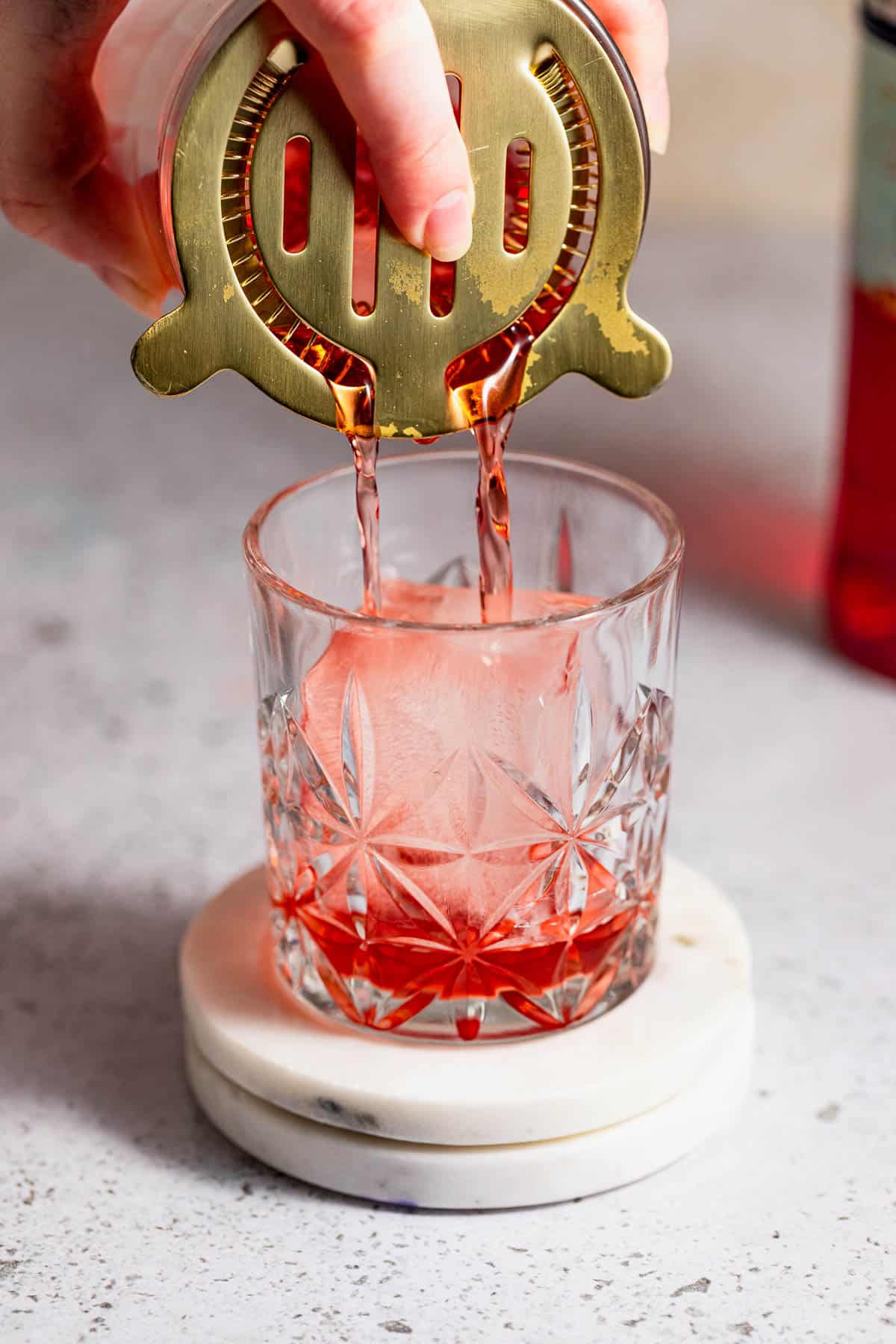 A mezcal negroni being poured into a rocks glass.