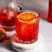 A glass of mezcal negroni sitting on a countertop.