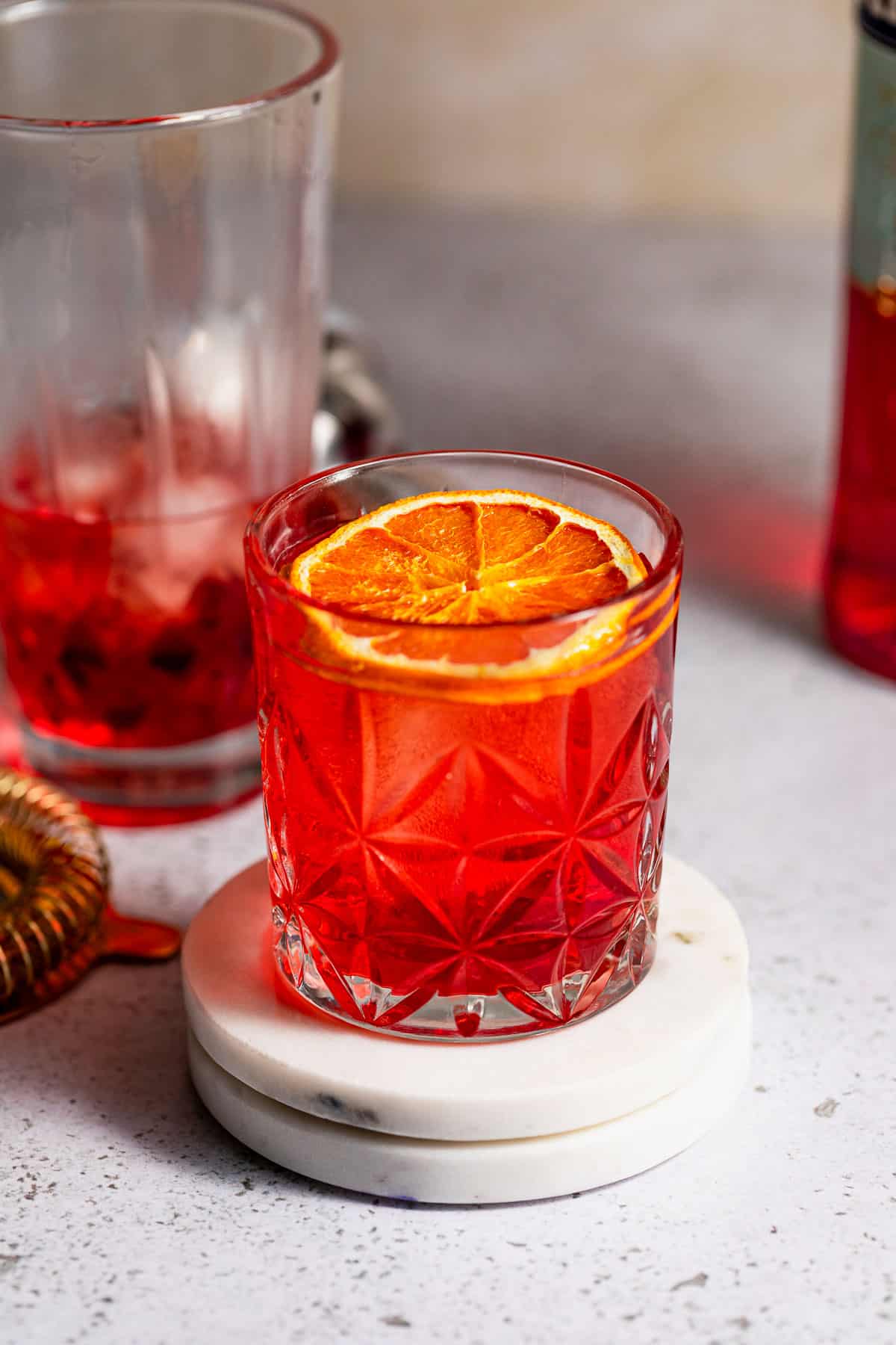 A glass of mezcal negroni sitting on a countertop.