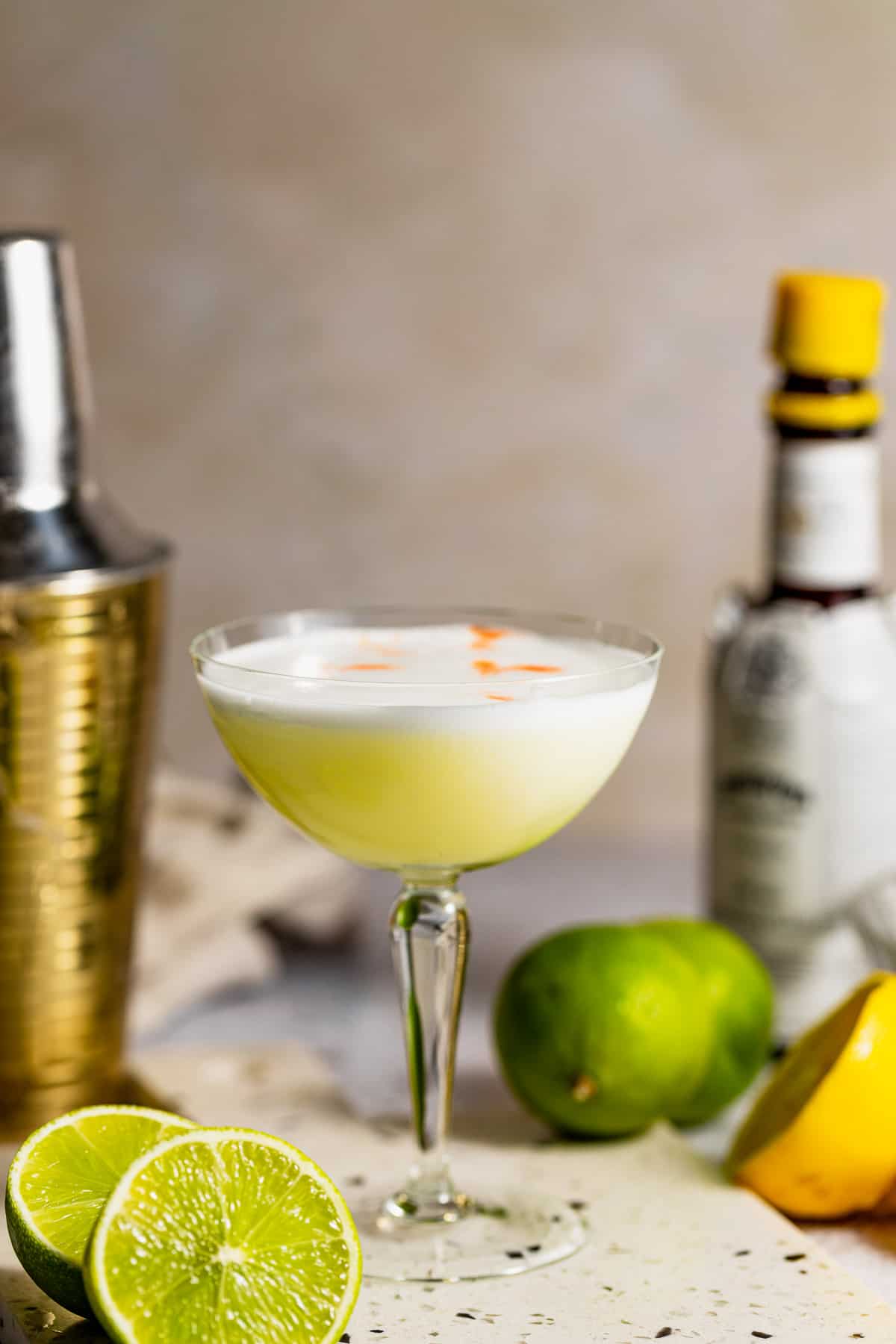 A mezcal sour served in a coupe glass sitting on a marble tray.