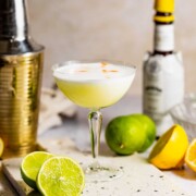 A mezcal sour cocktail served in a coupe glass sitting on a marble tray.