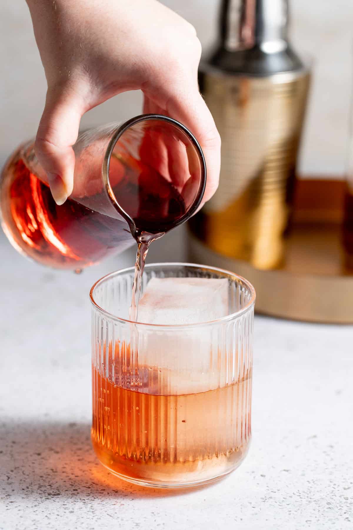 Cranberry juice being poured into a royal flush cocktail.