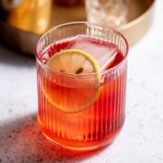 A royal flush cocktail garnished with a lemon slice sitting on a countertop.