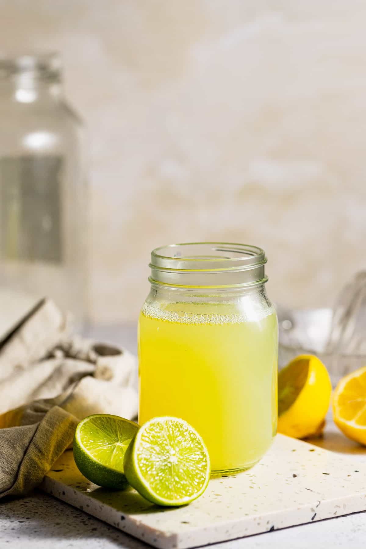 A mason jar filled with sweet and sour cocktail mix sitting on a marble cutting board.