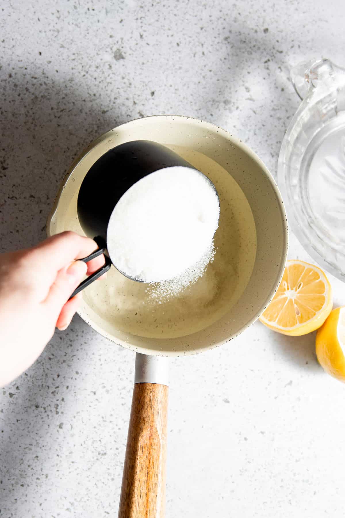 Sugar and water being added to a saucepan.